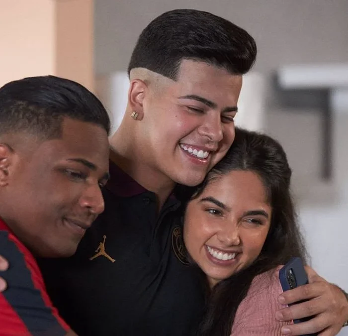 Nando (Christian Malheiros), Doni (Jotappê), Rita (Bruna Mascarenhas) se abraçando na série "Sintonia", da Netflix.