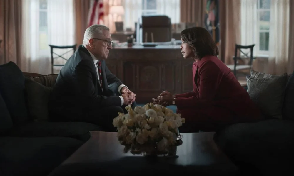 Robert Deniro, à esquerda, e Angela Basset, à direita, em dois sofás diferentes, se olhando. Há uma mesa ao centro na frente da cãmera e um buquê branco. Eles estão no Salão Oval e são os presidentes George Mullen e Evelyn Mitchell, conversando na série "Dia Zero", da Netflix.