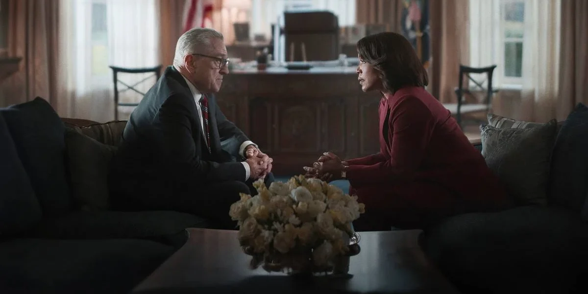 Robert Deniro, à esquerda, e Angela Basset, à direita, em dois sofás diferentes, se olhando. Há uma mesa ao centro na frente da cãmera e um buquê branco. Eles estão no Salão Oval e são os presidentes George Mullen e Evelyn Mitchell, conversando na série "Dia Zero", da Netflix.
