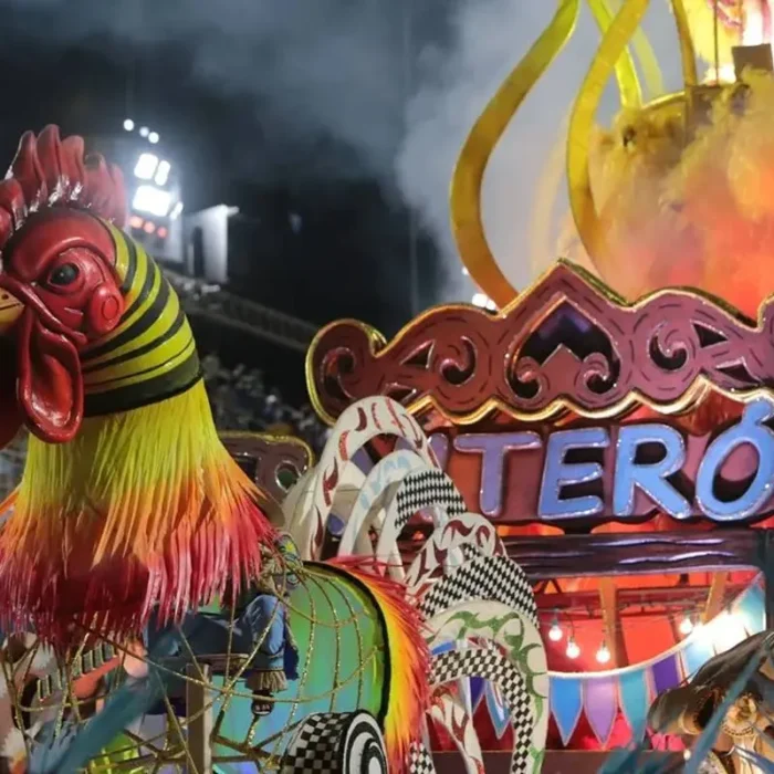 Foto de carro alegórico da escola de samba "Acadêmicos de Niterói", campeã da Série Ouro do Carnaval do Rio 2025. Há um galo gigante em destaque na frente.