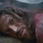 Can Yaman como o protagonista da série "O Turco". Ele possui uma arma sob sua cabeça e está prestes a ser atacado.