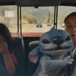 Lilo à esquerda, rindo, e Nani, à direita, preocupada, no volante, mas observando o alien Stitch dirigir o carro. Imagem do live-action de 2025 "Lilo & Stitch".