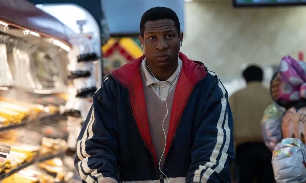 Jonathan Majors como o protagonista de "Magazine Dreams", com uma jaqueta andando em um mercado.