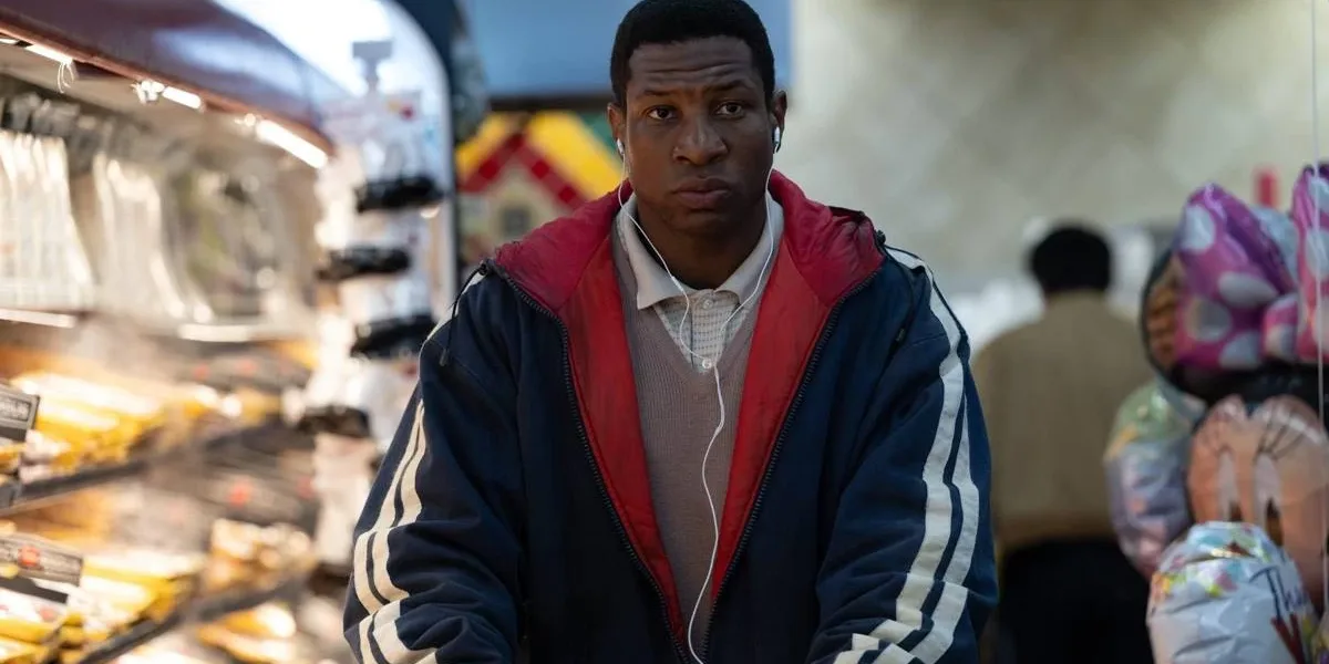 Jonathan Majors como o protagonista de "Magazine Dreams", com uma jaqueta andando em um mercado.