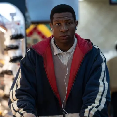 Jonathan Majors como o protagonista de "Magazine Dreams", com uma jaqueta andando em um mercado.