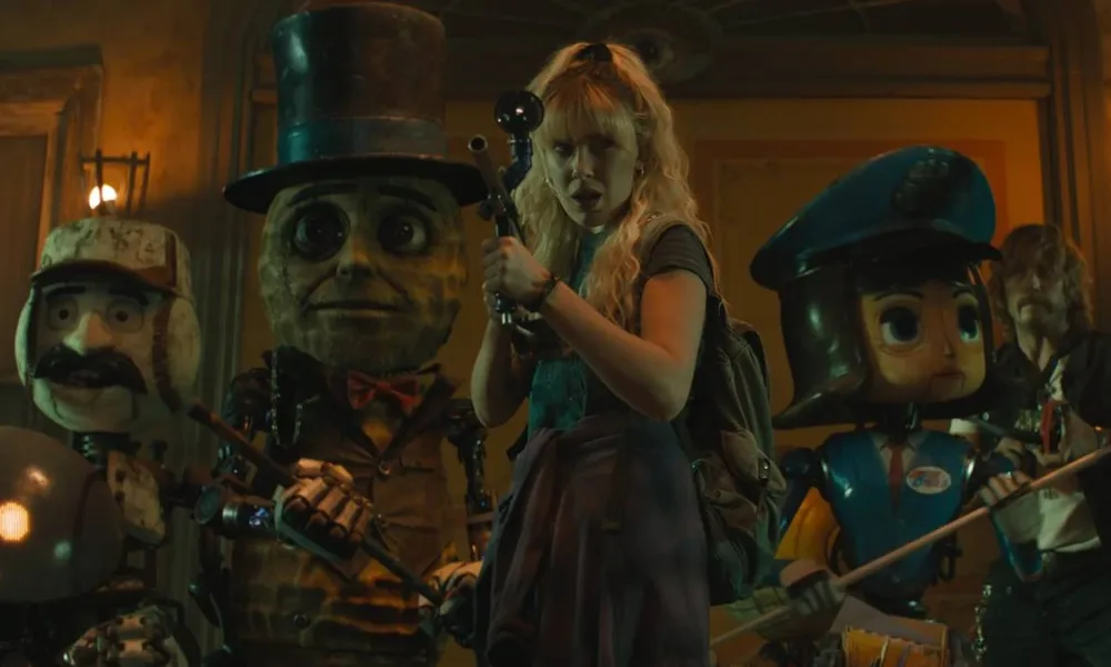 Millie Bobby Brown lutando ao lado de autômatos, todos com armas. No fundo está Chris Pratt. Imagens do filme "The Electric State", da Netflix. Atores usam visuais dos anos 90 para seus personagens.