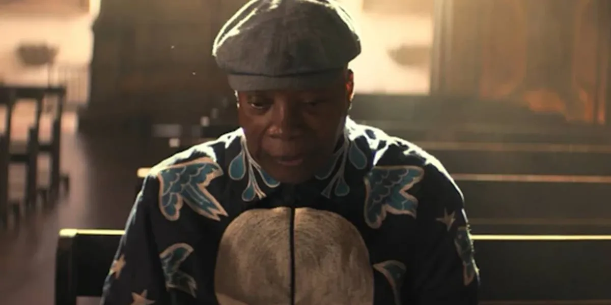 Milton Bituca Nascimento | Pré-estreia Com a Presença do Homenageado no Rio Milton Bituca Nascimento sentado, reflexivo, cabeça um pouco baixa, usando uma boina e roupa estampada escura com detalhes coloridos em azul e branco. O fundo é de uma igreja, na qual ele senta em um dos bancos.