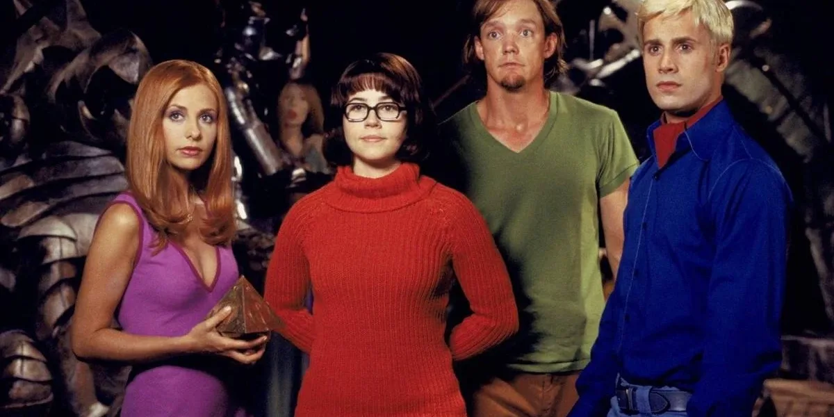 Netflix | Scooby-Doo Ganha Série Live-action Daphone, Velma, Salsicha, Fred, nessa ordem, encarando alguém do "lado da câmera" no live-action de Scooby-Doo de 2002. Eles estão com as roupas tradicionais da série de animação e Daphne segura um prisma.