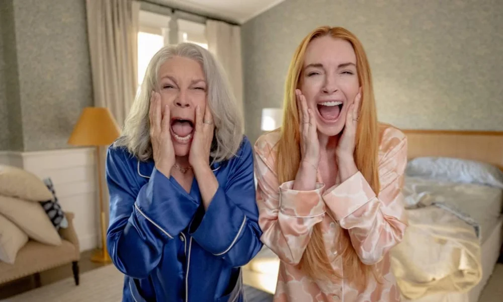 Jamie Lee Curtis, esquerda, e Lindsay Lohan, direita, como protagonistas da sequência de "Sexta Feira Muito Louca": "Uma Sexta Feira Mais Louca Ainda". Elas estão de pijamas, azul e bege, respectivamente, e gritando de horror ao se olharem em um espelho que está na posição da câmera/do telespectador.