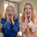 Jamie Lee Curtis, esquerda, e Lindsay Lohan, direita, como protagonistas da sequência de "Sexta Feira Muito Louca": "Uma Sexta Feira Mais Louca Ainda". Elas estão de pijamas, azul e bege, respectivamente, e gritando de horror ao se olharem em um espelho que está na posição da câmera/do telespectador.