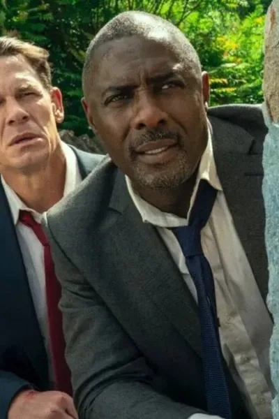 Chefes de Estado | Ação e Diversão Literalmente Em Dose Dupla John Cena (esquerda e atrás) e Idris Elba (direita e frente), escondidos atrás de um muro vestindo ternos na comédia "Chefes de Estado".
