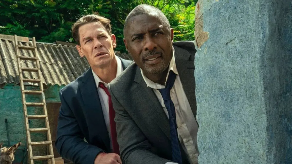 Chefes de Estado | Ação e Diversão Literalmente Em Dose Dupla 2 John Cena (esquerda e atrás) e Idris Elba (direita e frente), escondidos atrás de um muro vestindo ternos na comédia "Chefes de Estado".
