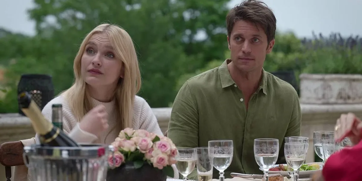 Lucas Bravo a direita da imagem sentado em uma mesa ao ar livre. Ator fez críticas a própria série "Emily in Paris". Imagem do oitavo episódio da segunda temporada.