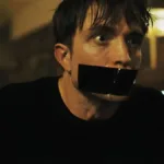 Robert Pattinson em "Mickey 17" como o protagonista, imobilizado e com a boca tapada por uma fita isolante.