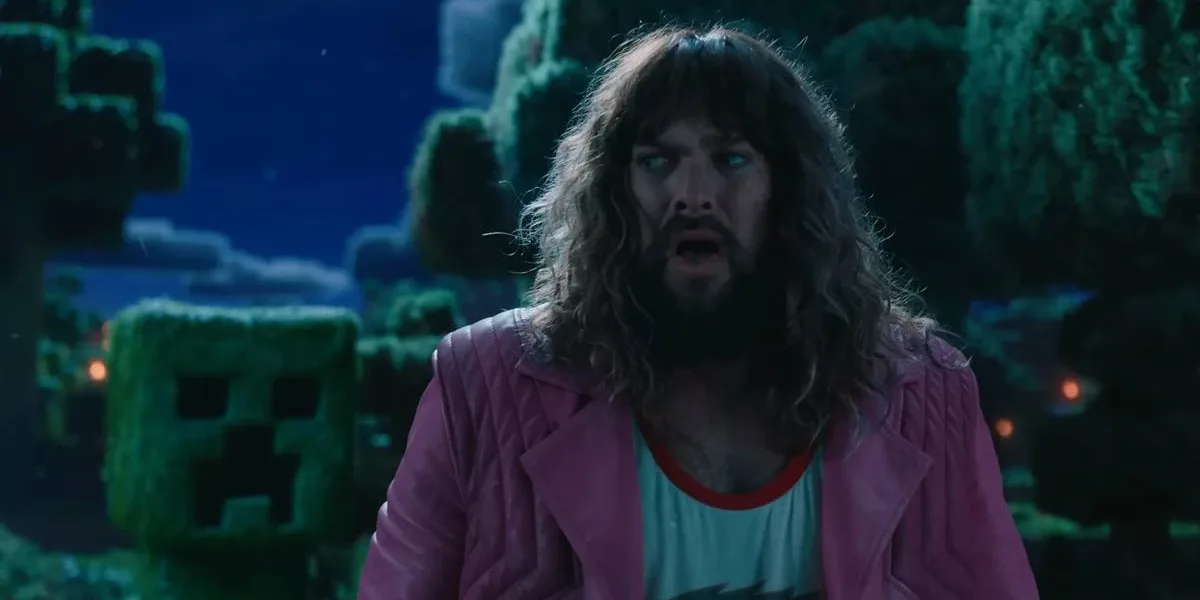 “Um Filme Minecraft” Estreia Quebrando Recordes e Consolida o Sucesso de um Fenômeno dos Games Jason Momoa boquiaberto e com medo interpretando Garrett em "Um Filme Minecraft". Atrás dele há um Creeper, prestes a explodir. Está de noite.