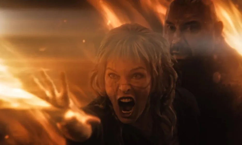 Personagem de Milla Jovovich tentando proteger o de Dave Bautista em "Nas Terras Perdidas". Eles interpretam respectivamente Gray Alys e Boyce.