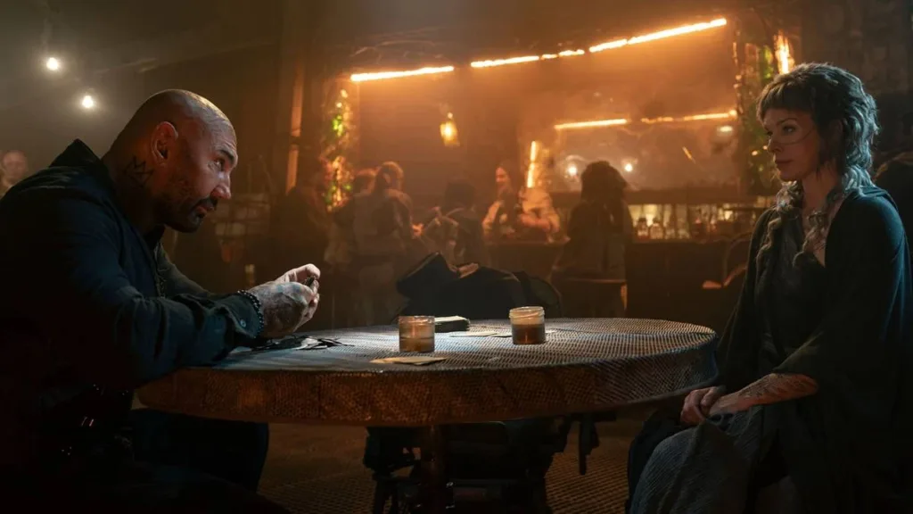 Nas Terras Perdidas | A Volta De Milla Jovovich e do Diretor Paul W.S. Anderson À Ficção e Aventura 1 Boyce, esquerda, e Gray Alis, direita, conversando em um bar. Ele olha para ela e ela desvia o olhar. Imagem do filme "Nas Terras Perdidas".