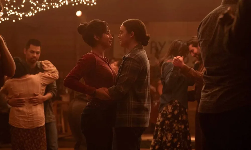Isabela Merced (esquerda) e Bella Ramsey (direita) dançando juntas, como um casal, na festa de ano novo da cidade de Jackson em "The Last of Us". Elas interpretam Dina e Ellie.