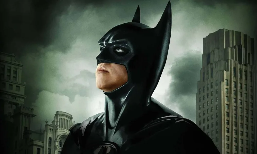 Val Kilmer como o Batman de "Batman para Sempre", olhando para o céu cinza de Gotham.