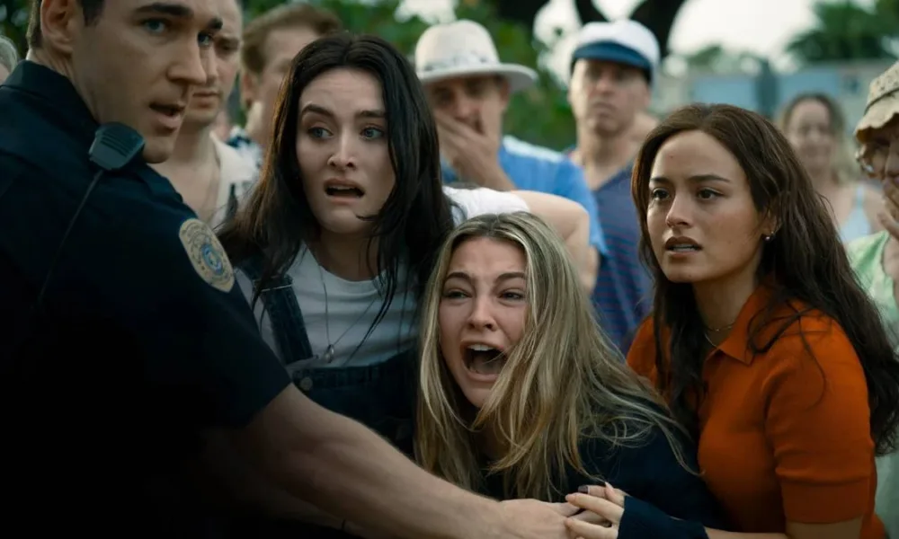 Imagem de divulgação do reboot de "Eu sei o que vocês fizeram no verão passado", com jovens sendo contidas, assustadas, pela polícia, ao presenciar alguma cena que não podemos ver,