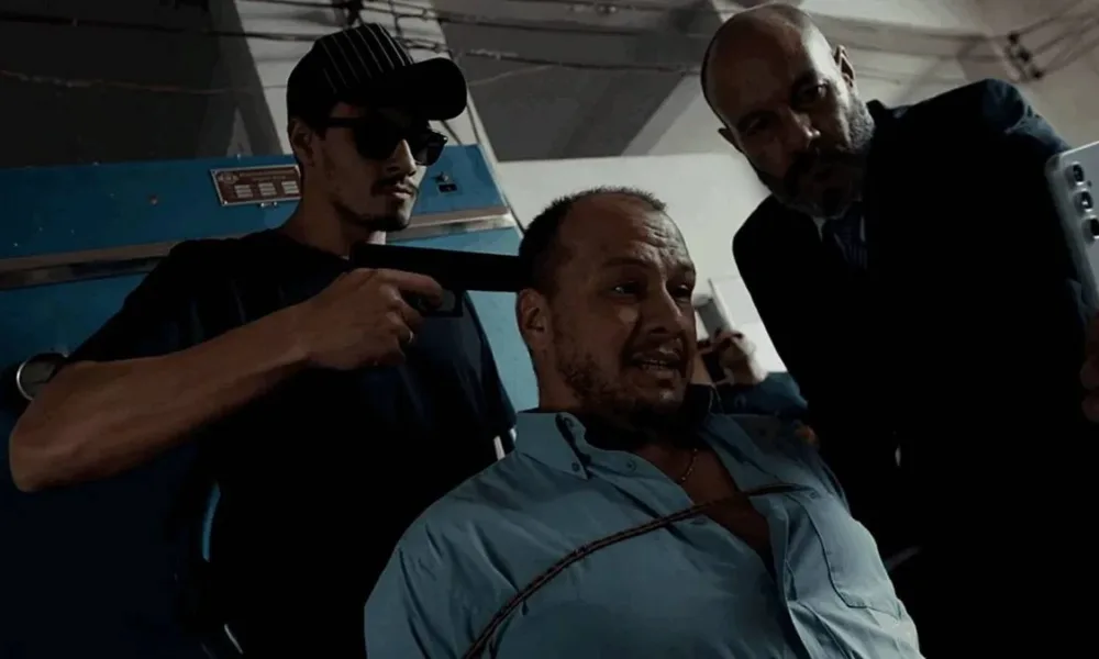 Personagem de Leandro Faria em "Do Sul, A Vingança" com uma arma na cabeça, sendo mantido refém, enquanto amarrado no filme.