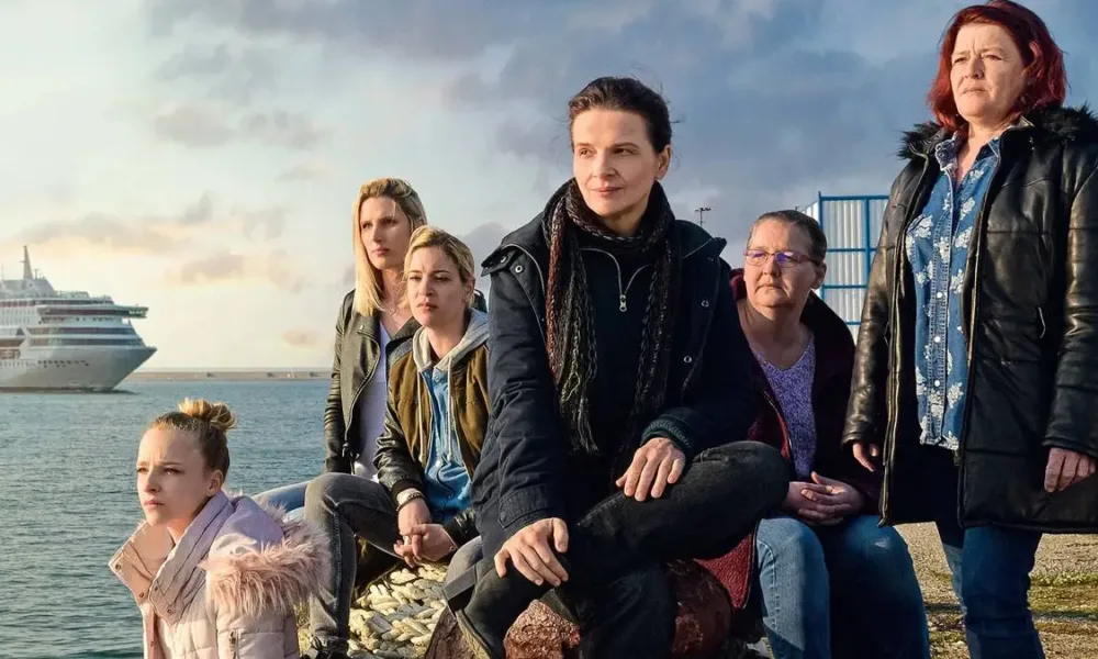 Elenco do filme francês "Entre Dois Mundos" (2022) sentado em um cais.