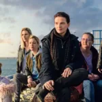 Elenco do filme francês "Entre Dois Mundos" (2022) sentado em um cais.