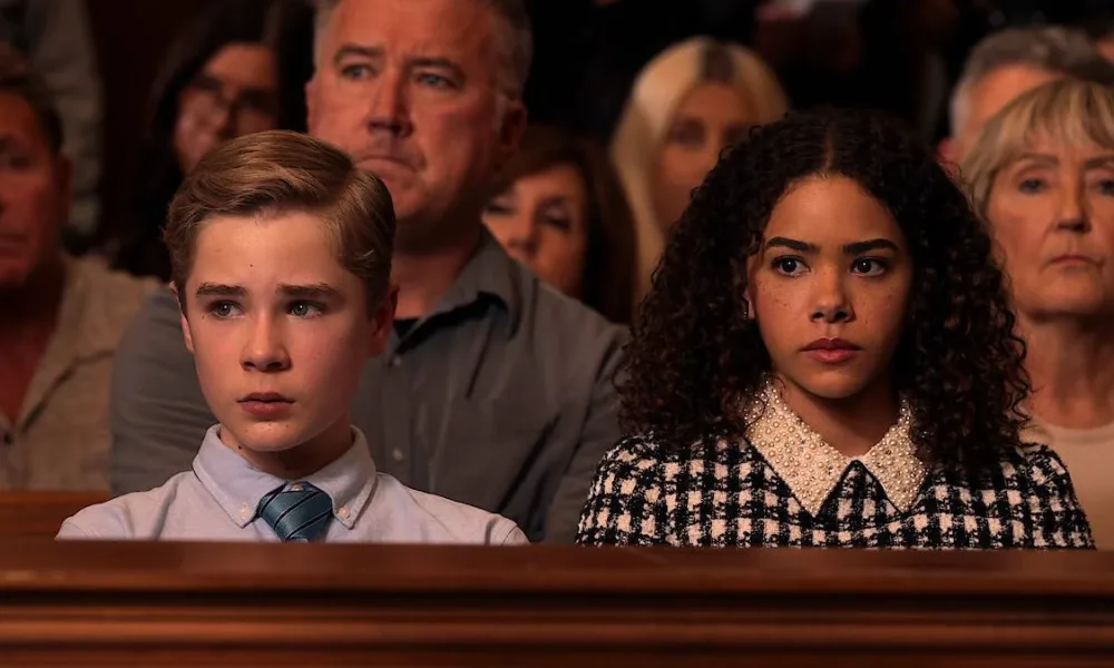 Austin (esquerda) e Ginny (direita) sentados assistindo au julgamento de sua mãe, Georgia, num tribunal na série "Ginny e Georgia", temporada 3.