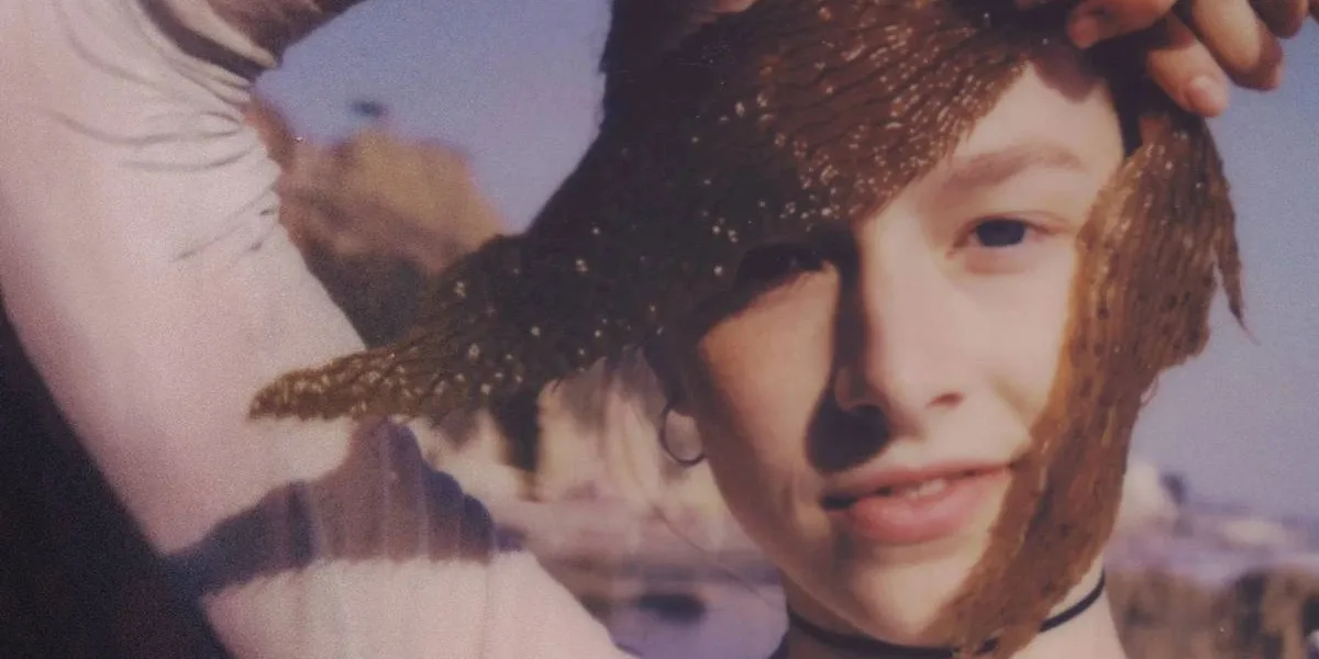 The Legend of Zelda | Hunter Schafer Pode Interpretar o Papel-título no Live-action HUnter Schafer interpretando Jules em "Euphoria". Atriz está com braço direito levantado (nossa esquerda da tela), olhando diretamente para a câmera, semi-dobrado, segurando duas folhas douradas pendentes, e um sorriso mostrando parcialmente os dentes de baixo.