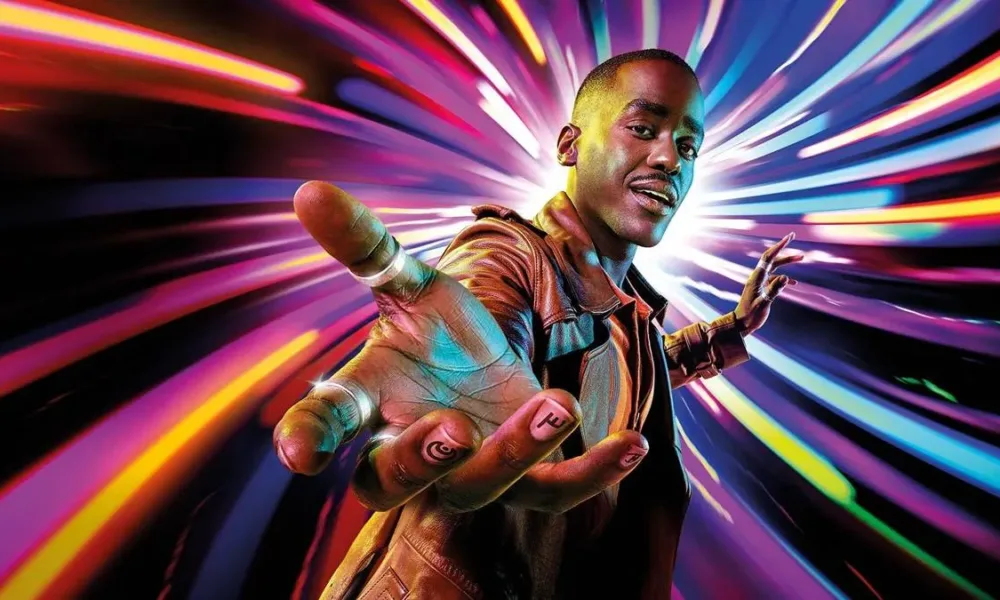 Ator Ncuti Gatwa como o Doutor de "Doctor Who" em série revival de 2024. Ele está dando as mãos para o telespectador, com ela em destaque para câmera, com um sorriso, e uma espiral futurística atrás dele.