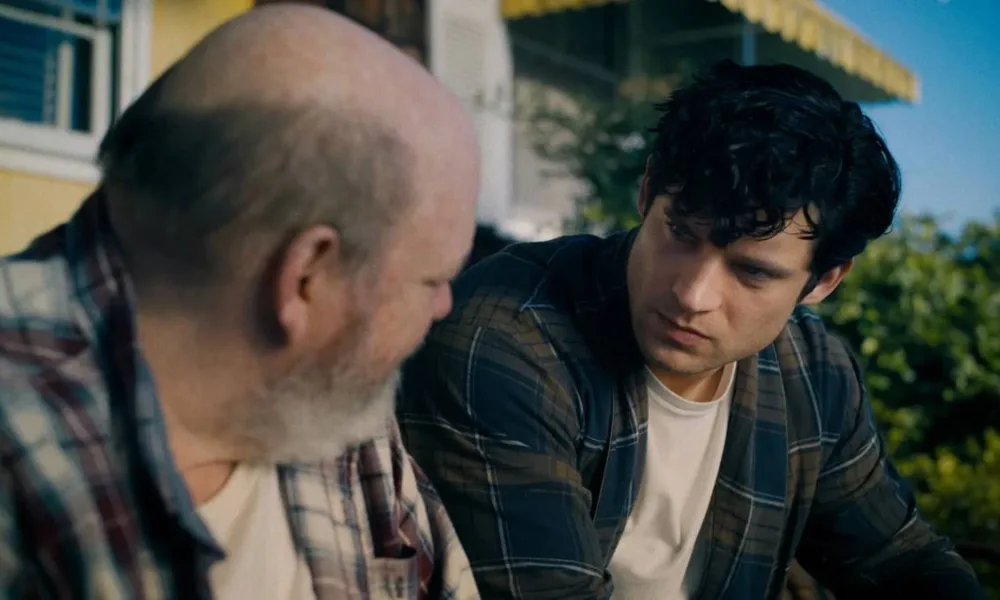 2º Trailer de Superman | Escrito e Dirigido por James Gunn, A Maior Aposta de DC, Traz Ação, Emoção e Aventura Trailer com David Corenswet, à direita, como o Superman no novo filme, homônimo, do herói, por James Gunn. Ele está sentado e como Clark Kent, conversando com um homem à esquerda, ambos de cabeça virada um ao outro.