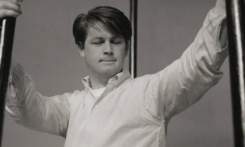 Brian Wilson, do Beach Boys, em foto em preto e branco de 1964, jovem, cabelo para o lado em franja, e camisa branca.