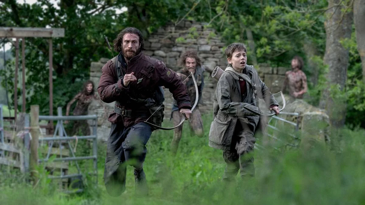 Extermínio: A Evolução | A Infecção Masculina 2 Jamie (Aaron Taylor-Johnson) e Spike (Alfie Williams) fugindo de três zumbis ao fundo deles em "Extermínio: A Evolução". Ambos carregam arcos e flechas.