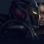 Riri Williams como a Coração de Ferro à direita da imagem, sua armadura, vista de perfil, está a sua frente.