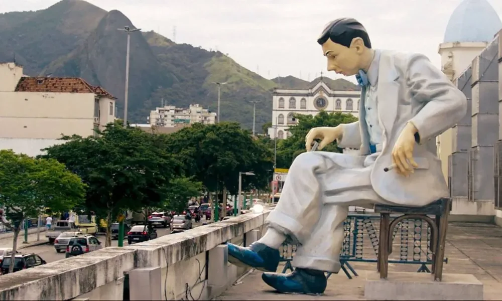 Uma estátua de Noel Rosa no Rio de Janeiro, conforme vista no documentário "Noel Rosa: Um Espírito Circulante".