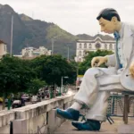 Uma estátua de Noel Rosa no Rio de Janeiro, conforme vista no documentário "Noel Rosa: Um Espírito Circulante".