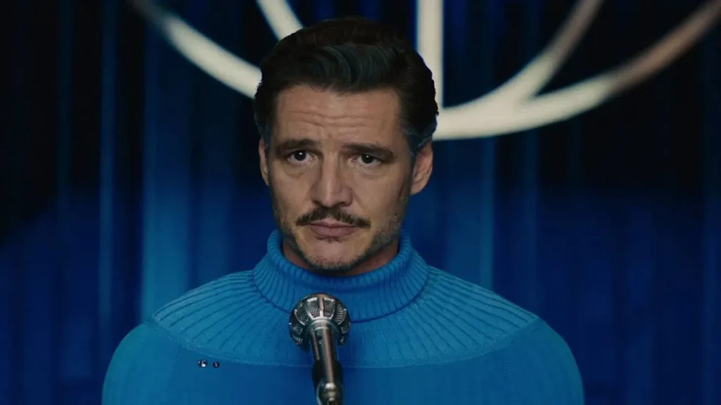 Kevin Feige Fala Sobre Futuro do MCU Após 2025 1 Pedro Pascal com suéter de gola alta azul da cor do uniforme do Quarteto Fantástico, no filme de mesmo nome, 2025, onde interpreta o Senhor Fantástico. Ele está centralizado na tela, com um microfone em sua frente.
