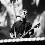 Noah Gallagher na guitarra em show do Oasis em Manchester em 12/07/2025. Imagem em preto e branco.