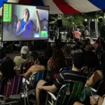 Djavan, o Musical: Vidas Pra Contar | Técnica e Conteúdo em um Espetáculo Memorável Exibição de filme pelo projeto Faz na Praça. Pessoas assistem a película em cadeiras de sol sob uma lona, em espaço aberto.