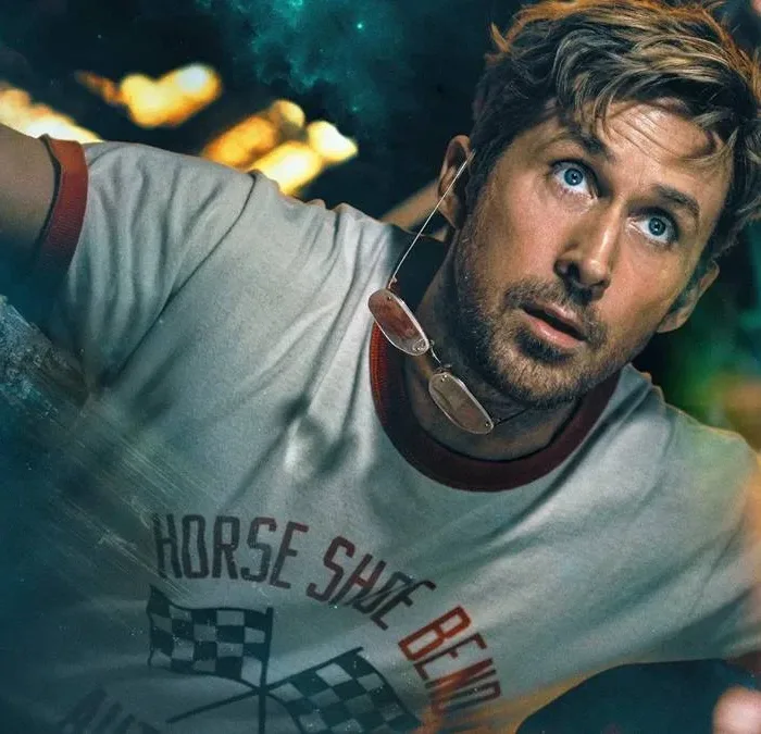 Ryan Gosling como protagonista de "Devoradores de Estrelas", da Sony, em que ele é visto atrás de um vidro, flutuando no espaço com uma camiseta de corrida branca. Ele olha para o outro lado com fascínio.