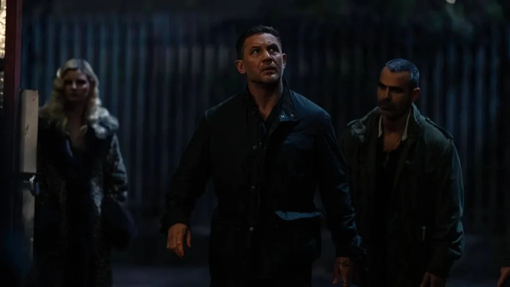 MobLand – Terra da Máfia | Série Surpreende com Caos, Loucura e Violência em Batalha de Gangsters na Londres Contemporânea 1 Tom Hardy ao centro e dois companheiros de cena em "Terra da Máfia". Ele caminha, olhando pelo ambiente atentamente.
