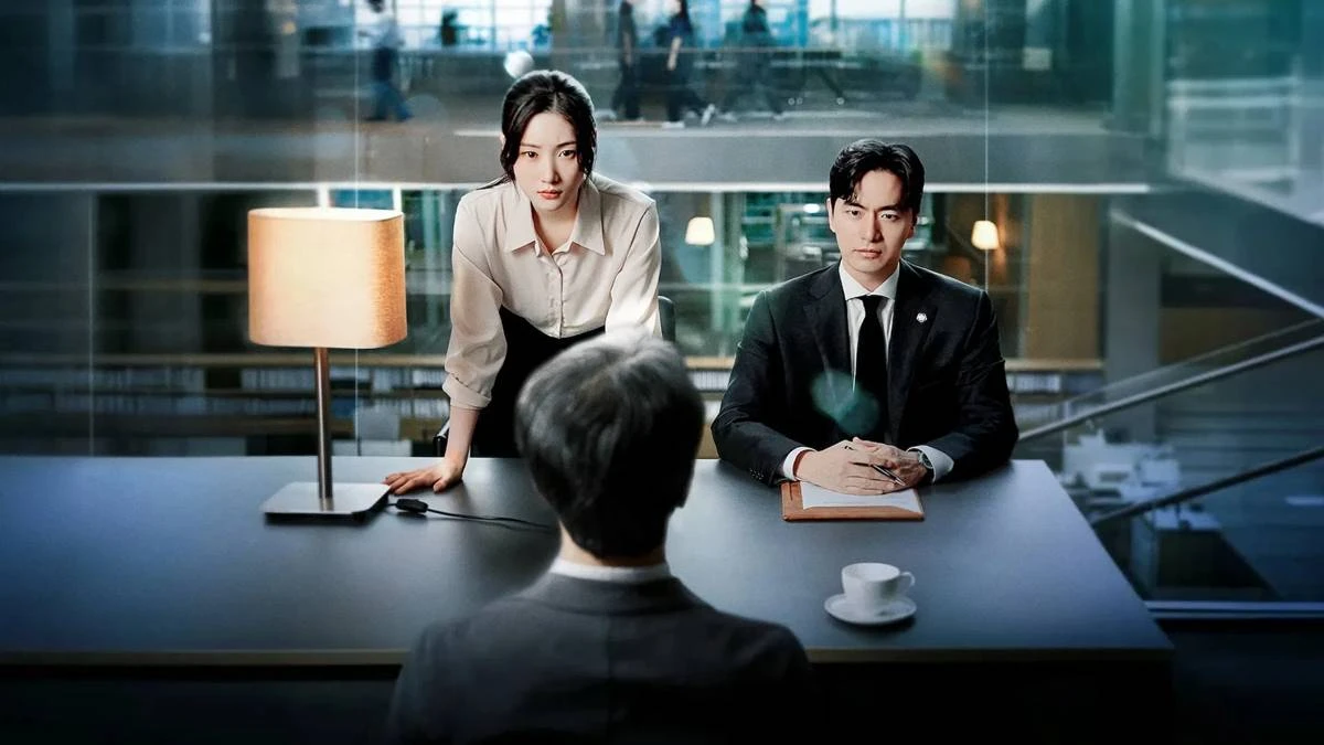 Além do Direito | K-Drama Mais Popular da Netflix Deixa Bem a Desejar 2 Protagonistas de "Além do Direito", os atores Jung Chae-yeon e Lee Jin-uk vestidos como advogados. Ela com as mãos apoiadas na mesa e corpo reclinado, ele com as mãos juntas e também com expressão séria. Do outro lado da mesa há um personagem masculino de costas, olhando para eles, contra a nossa câmera.