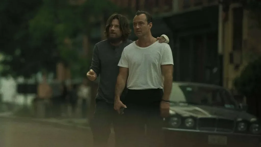 Jason Bateman, de cabelos longos, com a mão nos ombros de Jude Law. Ambos olham com espanto para o outro lado da tela. Ambos interpretam os protagonistas da futura série de Netflix "Black Rabbit".