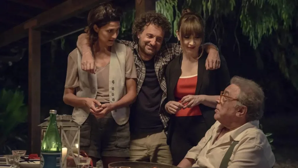 Faz De Conta Que é Paris | O Afeto a Partir de Falta Dele 1 Irmãos da comédia italiana "Faz de conta que é Paris" (2024) abraçados, de noite, em um restaurante improvisado, olhando para o pai.