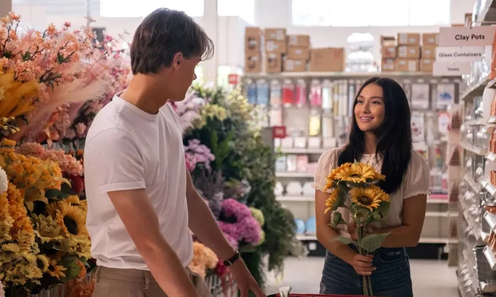 Conrad, de costas, virado à Belly, em 'O Verão Que Mudou Minha Vida', adaptação em série da Prime Video. Ela segura girassóis em uma floricultura.