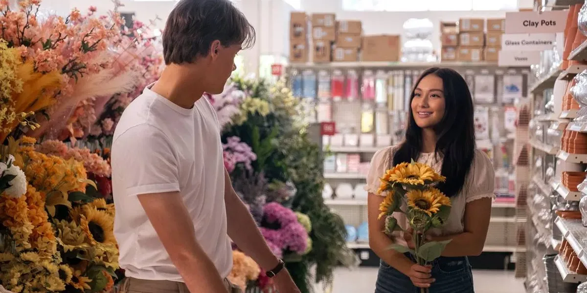 Conrad, de costas, virado à Belly, em 'O Verão Que Mudou Minha Vida', adaptação em série da Prime Video. Ela segura girassóis em uma floricultura.