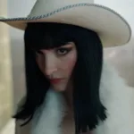 Lera Abovin como Nico Robin/Miss Sunday em primeiro trailer da segunda temporada de One Piece. Ela está com cabelos longos esticados, vestindo um casaco felpudo, e chapéu branco de cowgirl.