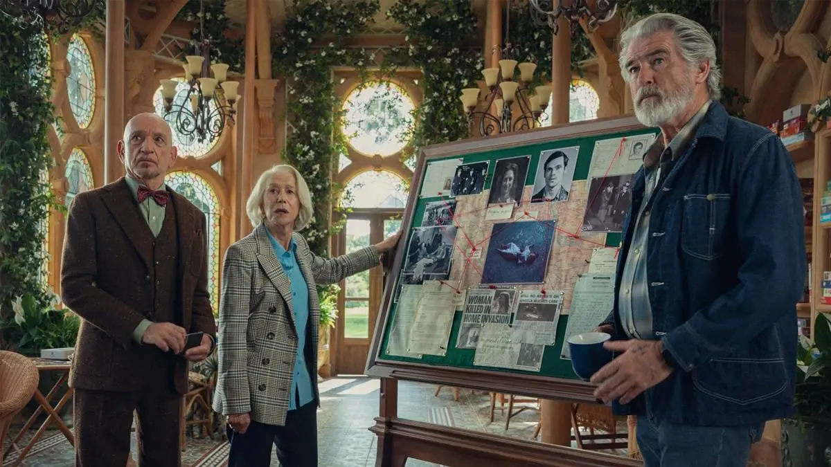 O Clube do Crime das Quintas-feiras | Mais Um Filme da Netflix, Dessa Vez Com Um Elenco Estelar 2 Na esquerda e mais ao fundo: Ben Kingsley e Helen Mirren, que segura o quadro, e à direita do quadro e mais à frente Pierce Brosnan. Atores interpretam seus personagens em "O Clube do Crime das Quintas-feiras", da Netflix, e estão ao lado de um quadro verde com mapa mental para resolução criminal, cheio de colagens, e olham para um mesmo ponto do outro lado da tela.