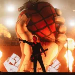 The Town 2025 | Iggy Pop Expõe o Peso de Seu Legado em Show Histórico Billie Joe Armstrong com mão direita levantada com microfone à plateia, em foto centralizado no palco Skyline do The Town 2025. Ao fundo há pirotecnia e uma representação da capa do álbum American Idiot esculpida.