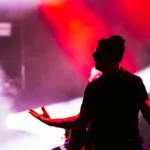 The Town 2025 | Bruce Dickinson Mostra Por Que Não Precisa do Iron Maiden Silhueta do vocalista do Bad Religion, vista sob luz vermelha atrás dele em apresentação no palco Skyline no The Town 2025.